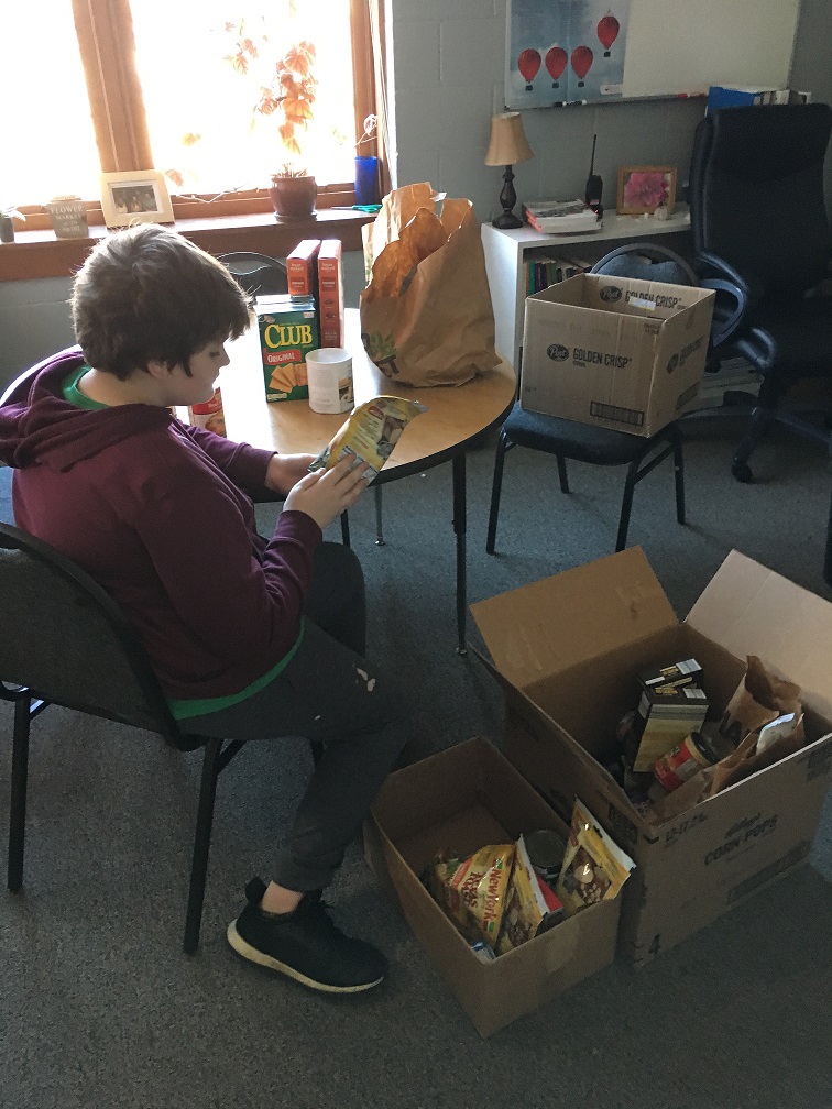 student helper checking expiration dates on food drive donations